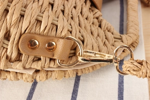 Detailed view of woven paper rope bag featuring gold metal hooks and brown leather straps
