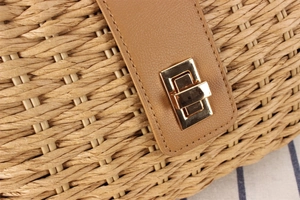 Macro detail of paper rope woven bag with golden rectangular turn-lock and brown leather strap