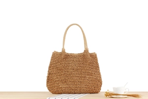 Close-up of handwoven textured paper rope bag with wave pattern on wooden surface