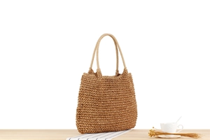 Detailed texture of brown hand-woven paper rope shoulder bag on a minimalist desk