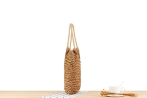 Detail view of woven shoulder bag featuring thick rope straps and textured paper straw craft