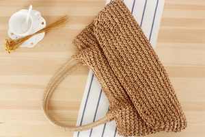 Detail of light brown handmade paper straw tote bag texture and woven handles