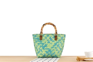 Detail of woven beach bag with bamboo handles on a blue striped table runner