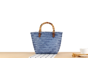 Detail of woven blue checkered handbag featuring natural bamboo handle and leather fasteners