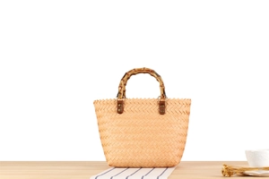 Close-up of handwoven straw handbag with vintage bamboo handle and leather fasteners