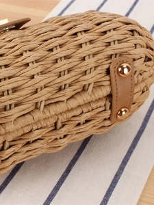Handwoven straw tote bag detail with brown leather straps and gold metal rivets