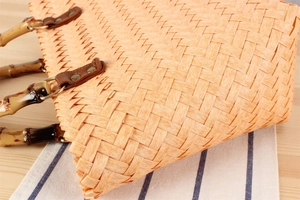 Detail of woven straw handbag featuring vintage bamboo handle and gold metal ring connectors