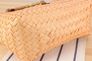 Detailed close-up of handmade woven beach bag featuring a natural bamboo handle design
