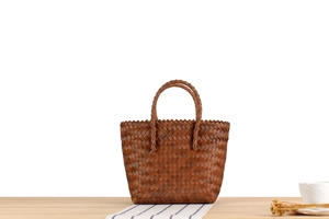 Detail of dark brown woven handbag showing intricate texture and circular handles