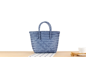 Close-up of blue woven tote bag with diamond pattern on a minimalist wooden surface