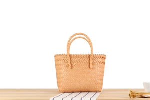 Detail of hand-woven straw basket bag with dual handles on a rustic wooden table setup