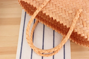 Detail of handwoven orange tote bag showing intricate texture and cylindrical handles
