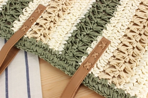 Detail of green and beige paper rope weave with leather handle and X-pattern stitching