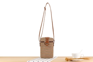 Detailed close-up of woven cylinder bag with striped pattern and gold metal lock hardware