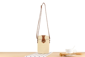 Detail view of woven cylinder bucket bag with brown leather strap and gold twist lock