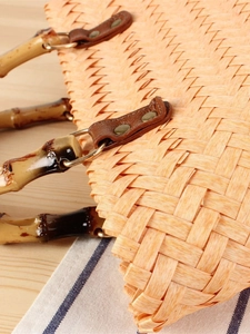 Handwoven straw beach bag featuring vintage bamboo handles and brown leather accents