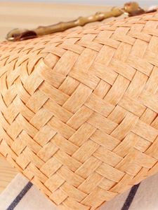 Retro hand-woven straw beach bag with bamboo handle on a natural wooden background