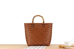 Detail of vintage woven handbag with bamboo handle on a wooden table setup