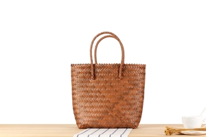 Detail of handcrafted brown woven tote bag showing texture on a wooden table setup