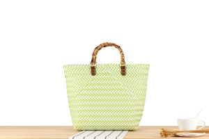 Detailed view of woven tote with green chevron pattern and bamboo top handle