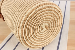 Detail of hand-woven paper rope cylinder bag showing natural texture and leather strap