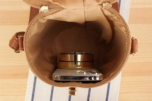 Detail view of the brown paper woven cylinder bag interior with phone and cosmetics