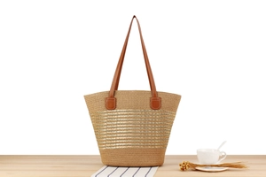Detailed macro view of woven tote bag with metallic stripes and faux leather handles