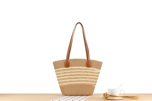 Detail of hand-woven striped tote bag with brown leather straps on a wooden surface