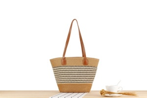 Detailed close-up of a striped woven tote bag with premium leather handles on a wooden table