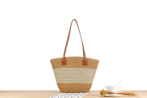 Close-up of the woven striped texture and brown leather straps on this straw tote bag