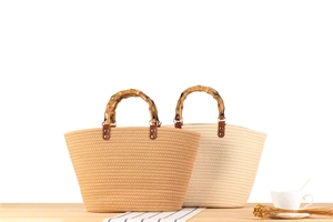 Dettaglio di borse in paglia intrecciata con manici in bambù in beige e marrone