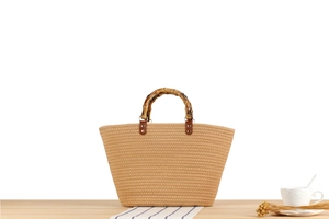 Dettaglio della borsa tote in paglia intrecciata con manici in bambù e rivetti