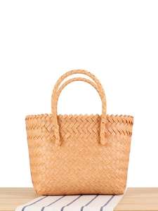 Handcrafted faux rattan woven tote bag with circular handles on a blue striped fabric