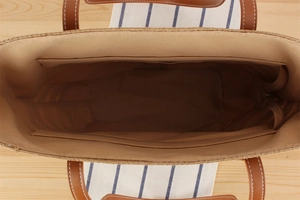 Top view of woven tote bag interior with fabric lining and leather straps