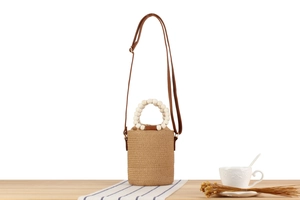Close-up of paper rope bucket bag with white wooden bead handle and brown leather strap