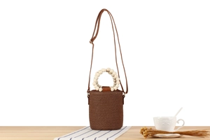 Detail of a brown woven bucket bag featuring unique cream wooden bead circular handles