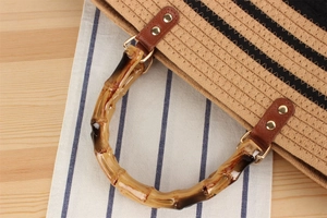 Dettaglio del manico in bambù con cinturini in pelle e rivetti dorati su borsa tessuta