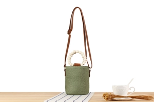 Detail of green straw bucket bag showing woven texture and white beaded handle