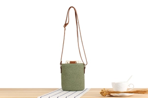 Close-up of green paper rope woven bucket bag with wood bead and brown leather strap