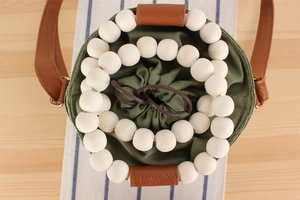 Top view of bucket bag with green canvas pouch and large white wooden bead decoration