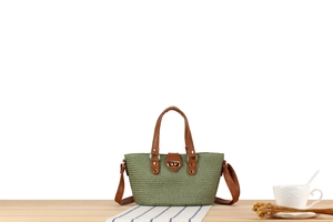 Close-up of green woven handbag featuring brown leather handles and gold twist lock clasp