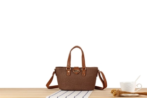 Detail of a brown woven tote bag featuring high-quality faux leather trim and gold metal lock