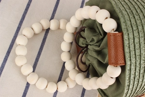 Detail of paper straw woven green bag with white wooden bead handle and drawstring closure
