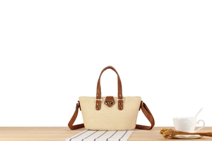 Detail of woven beige tote bag with dark brown leather straps and metal twist lock