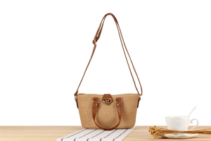 Close-up of woven straw handbag with brown leather handles and gold swivel lock detail