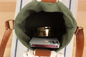 Top view of army green canvas bucket bag showing interior space with phone and compact