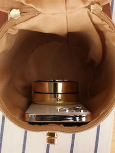 Brown woven cylindrical handbag interior showing capacity with phone and cosmetics