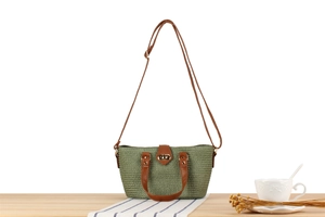 Detail of green straw woven bag with brown leather strap and golden turn-lock closure