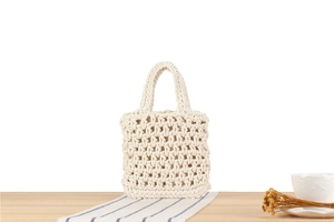 Close-up of handmade cream crochet tote bag with hollow woven texture on a wooden table