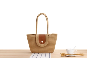 Detail of woven beach tote featuring a leather flap with an elegant pearl buckle closure